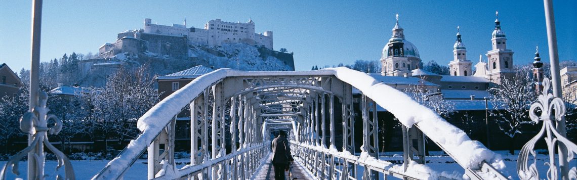 Verschneiter Mozartsteg mit Altstadt und Festung Hohensalzburg.
Mozart bridge in winter with view to the historic city center of Salzburg.